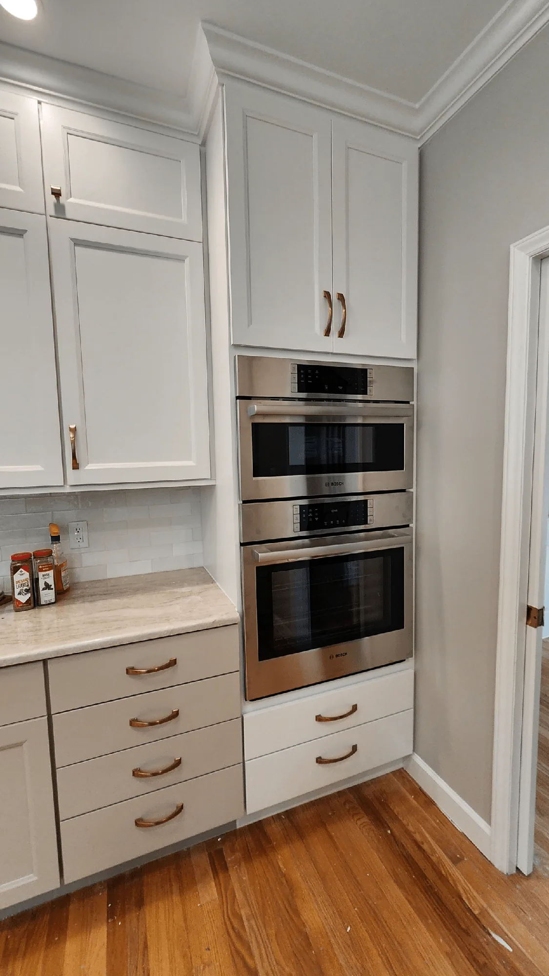 Tall custom cabinetry surrounding stacked kitchen appliances